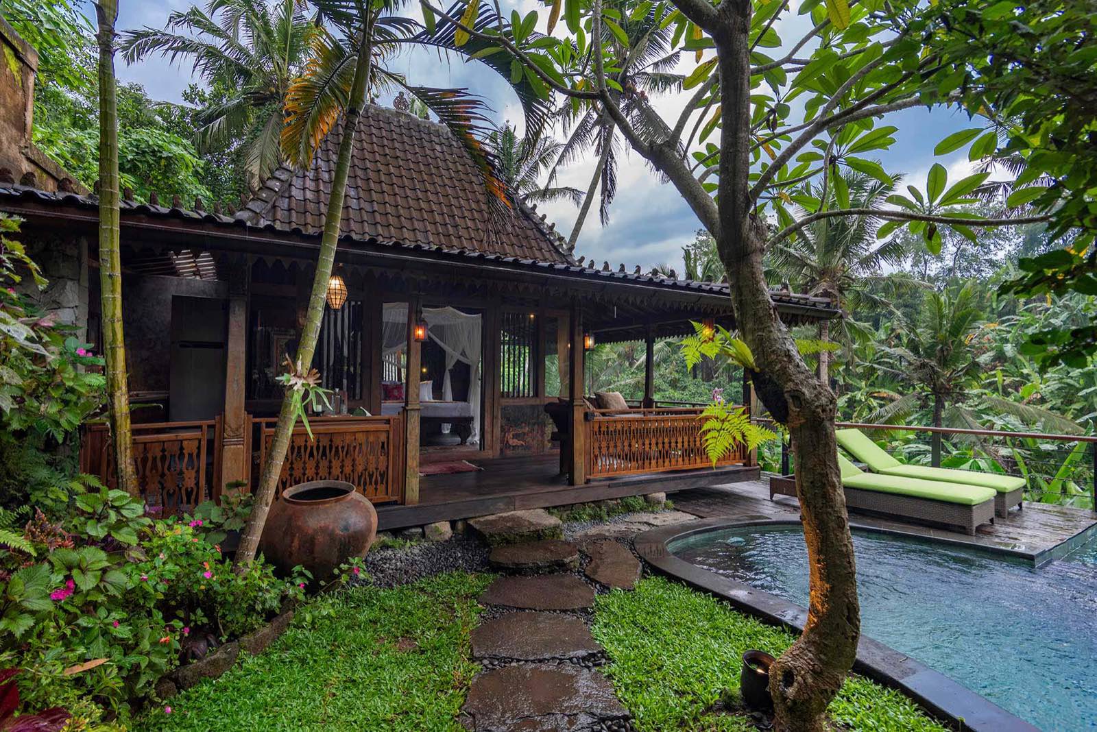 Jaguar Cottage, an antique teak Gladak with a wrap-around veranda, its salt-water pool and loungers set in the garden
